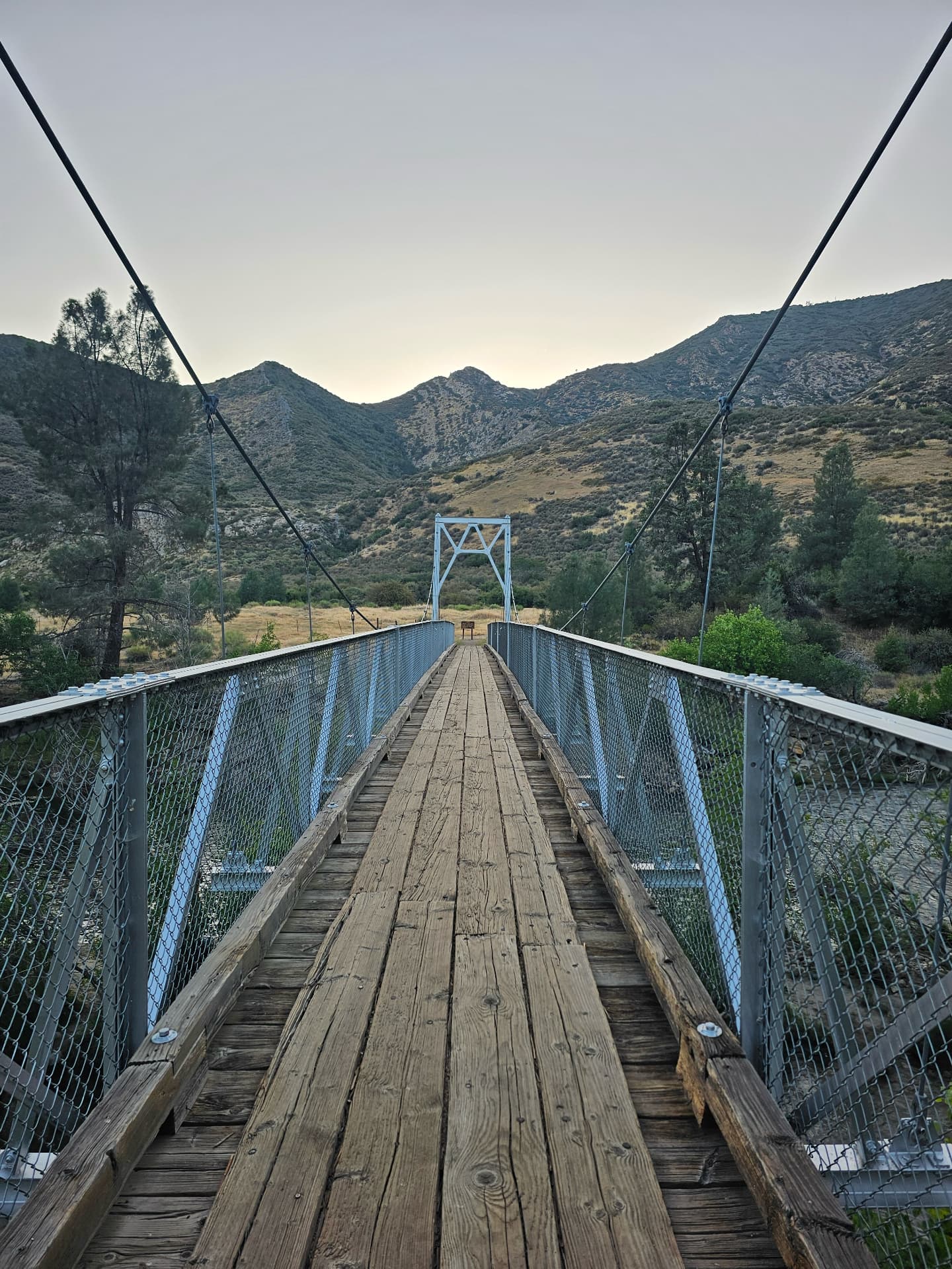 Wooden suspension footbridge over the river at dusk in Sequoia National Forest