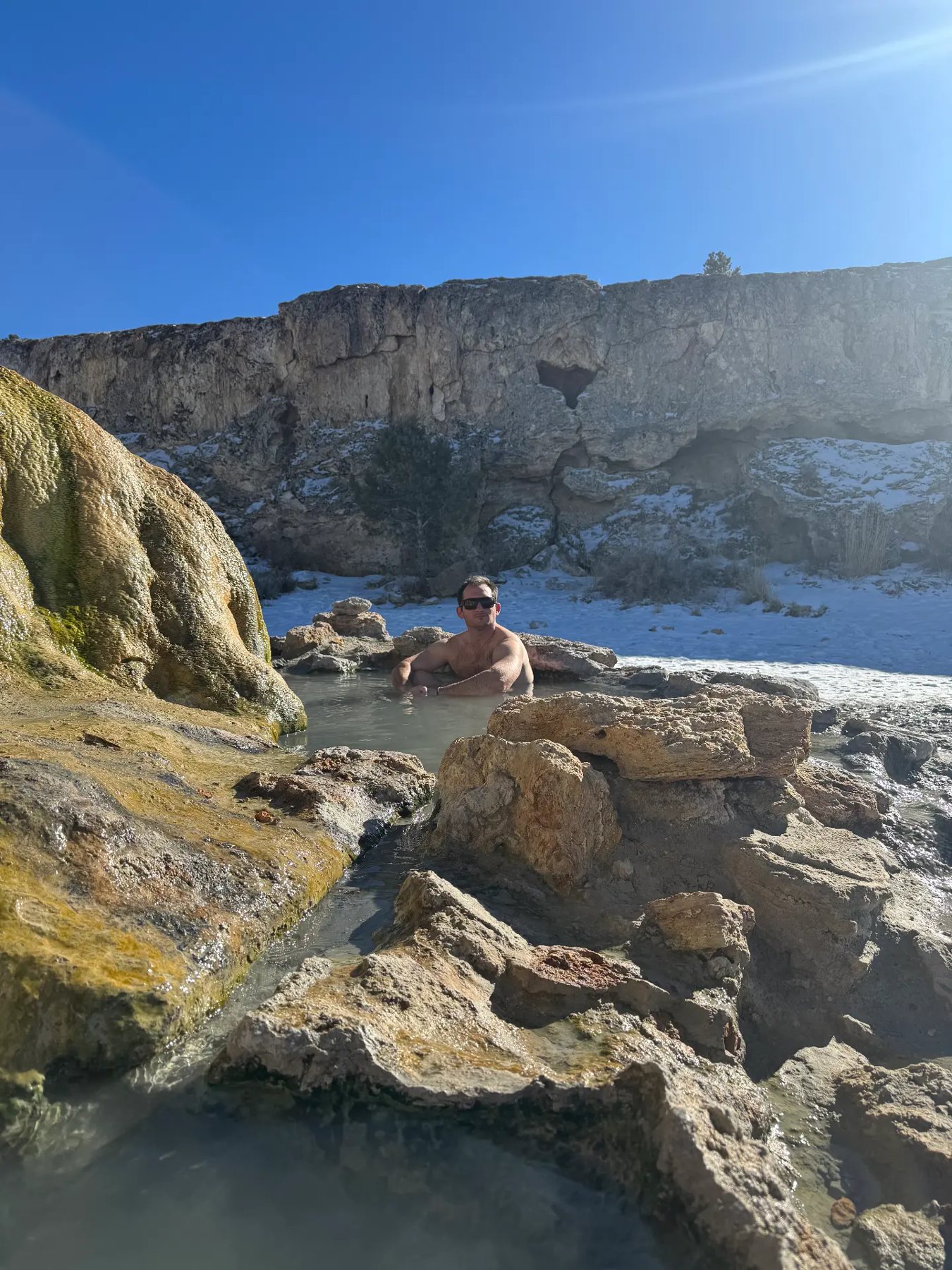 Soaking in the hot springs below the cliff band during a men's wilderness therapy trip