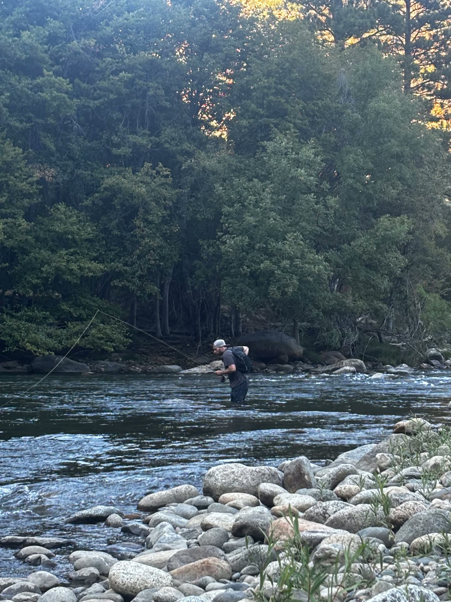 Man wading the river fly fishing at last light during a men's outdoor therapy trip