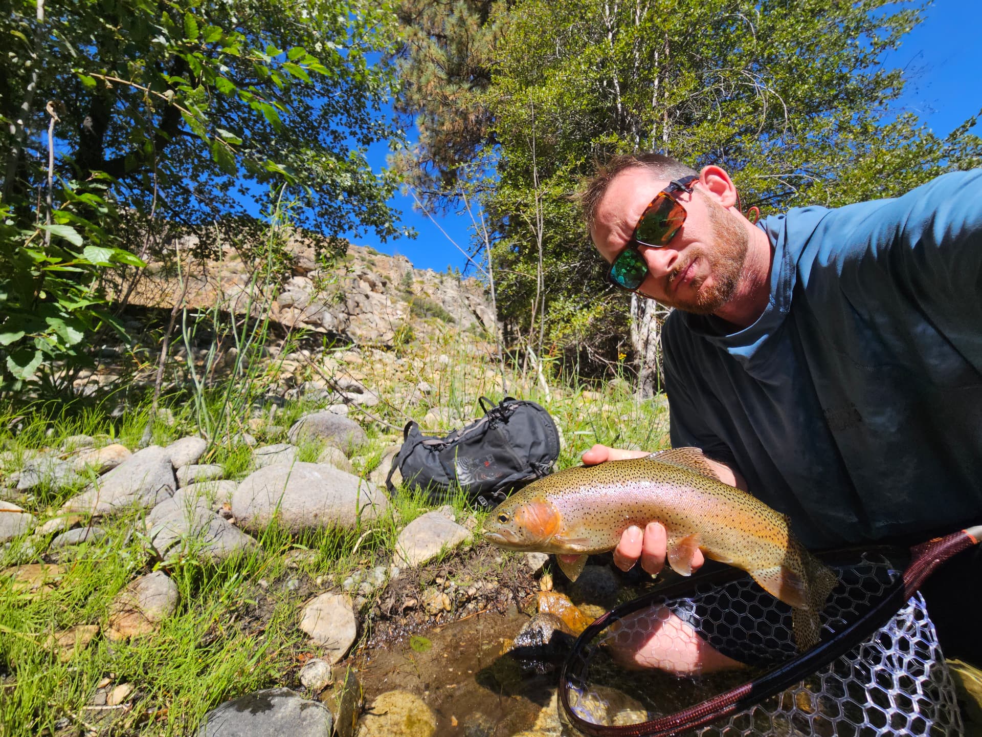 Holding a golden trout at the river's edge during a men's wilderness therapy trip in the Golden Trout Wilderness
