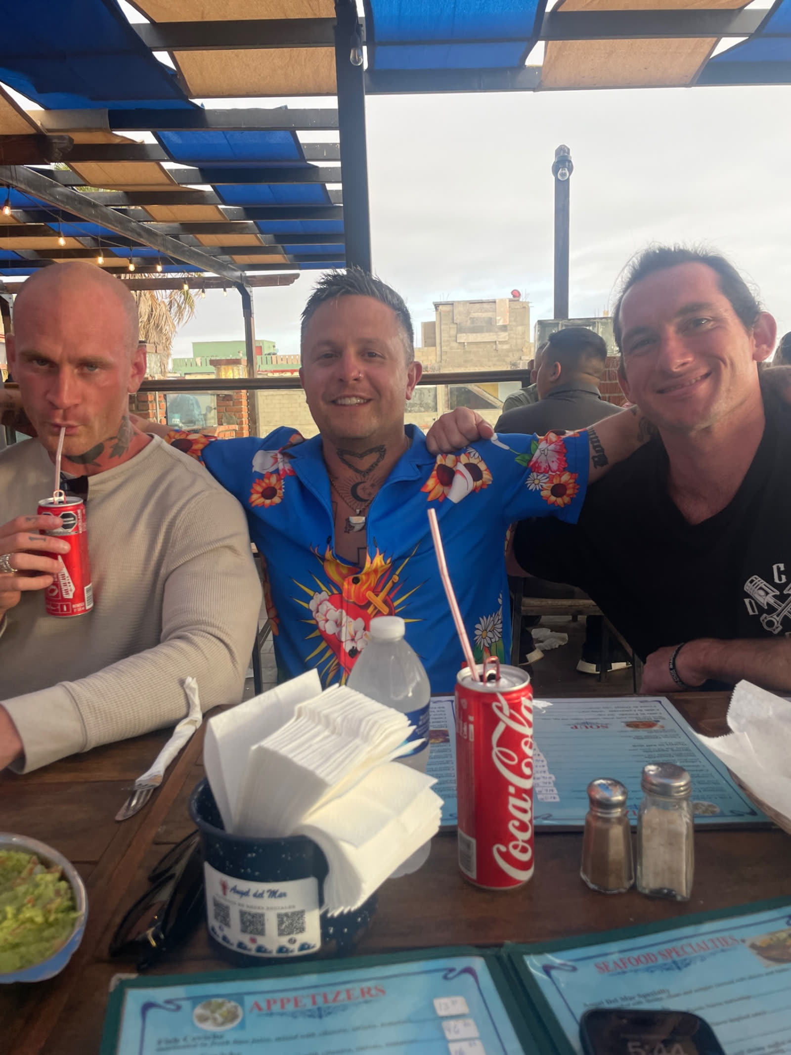 The group crowded around a seafood table under blue shade in Baja
