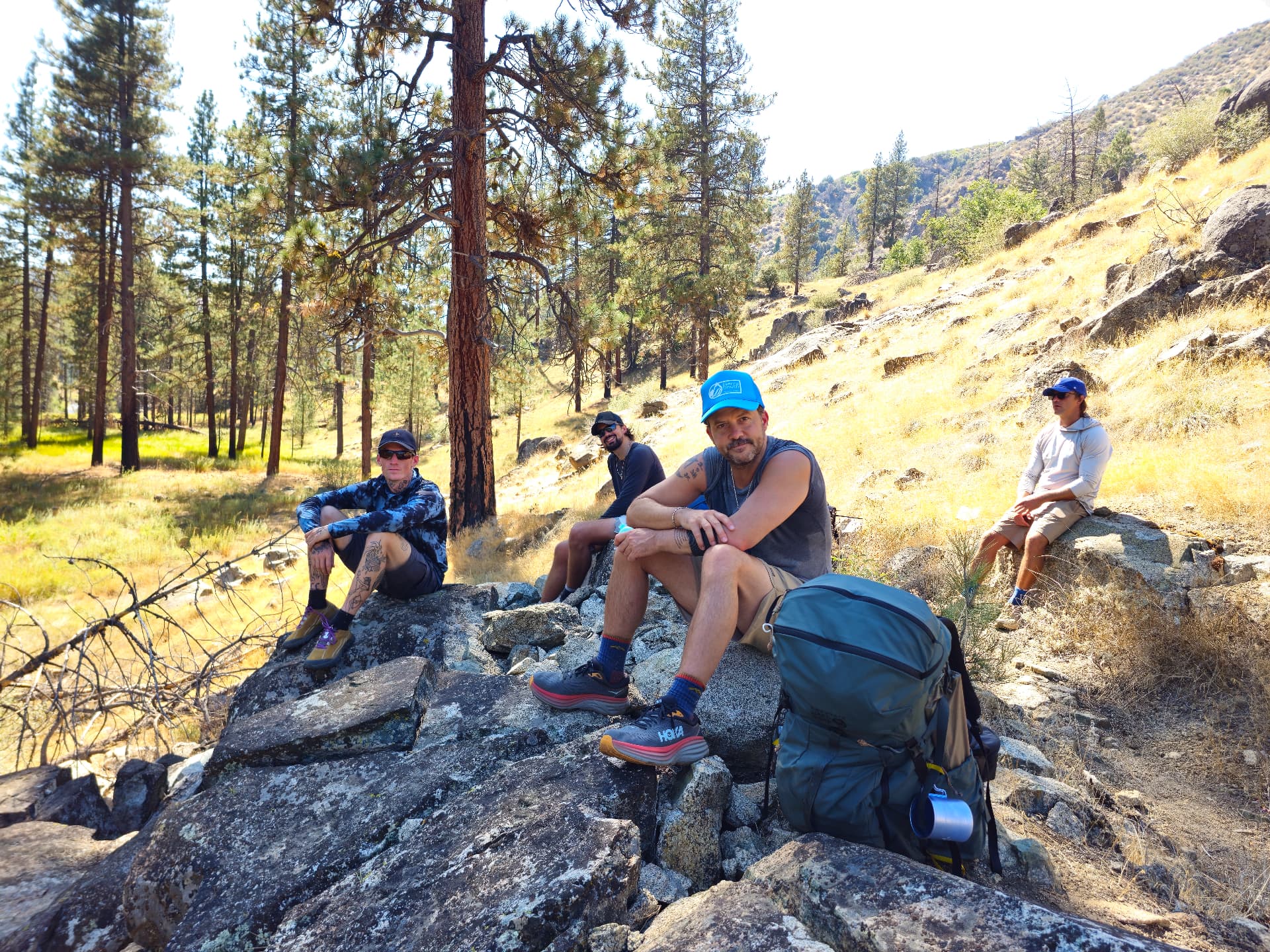 The group resting on granite boulders in the pines during a Recovery Republic camping trip