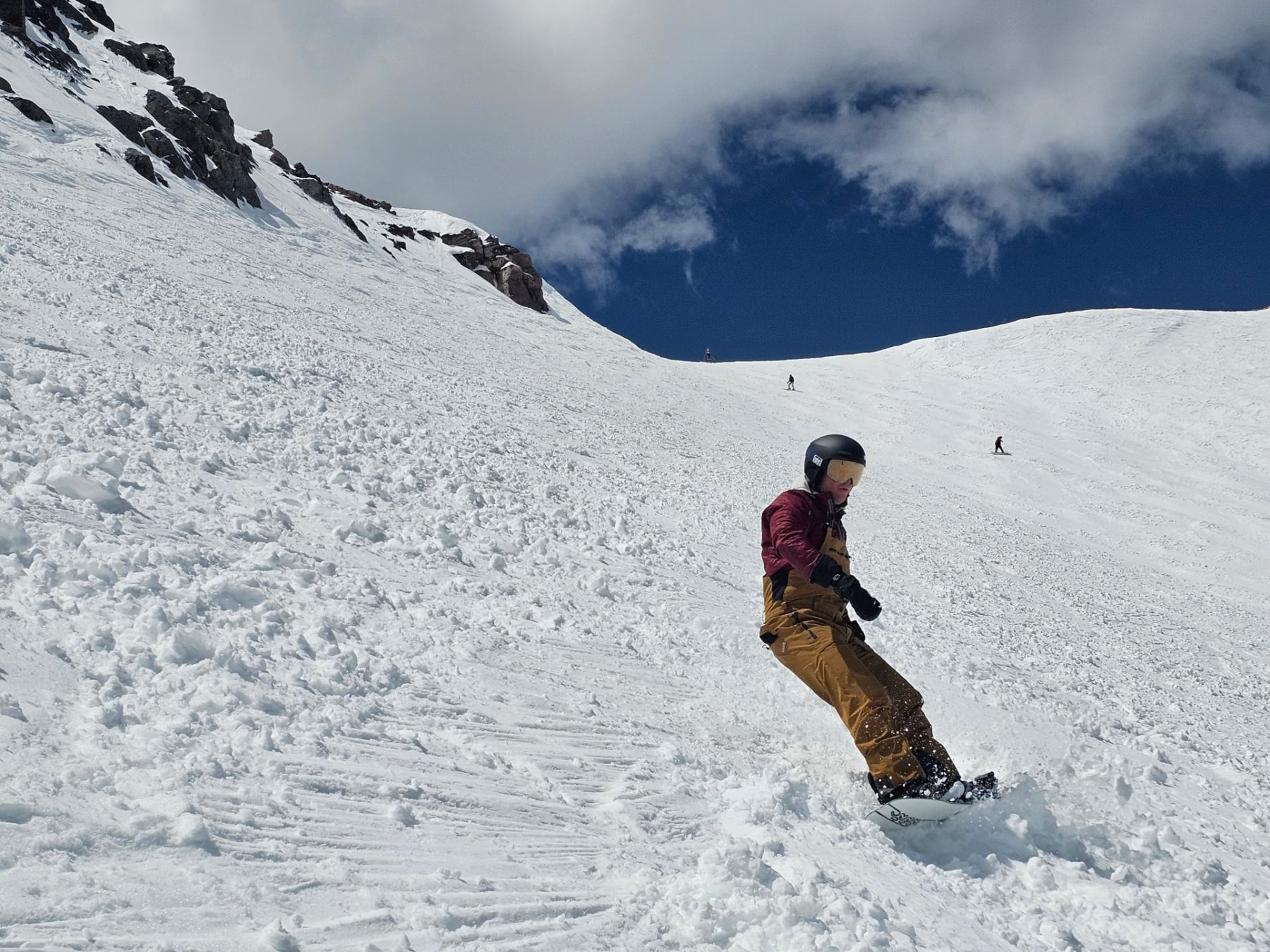 Men's outdoor therapy trip to Mammoth — snowboarder carving down a steep spring bowl